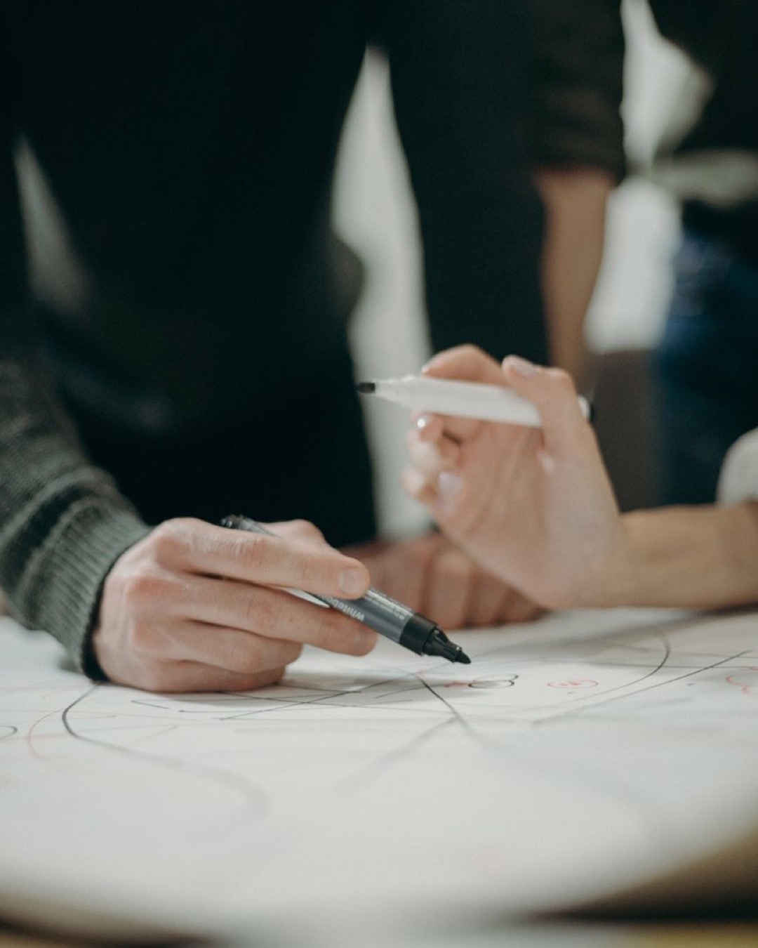 Two people collaborating, writing ideas and plans on paper during a meeting.
