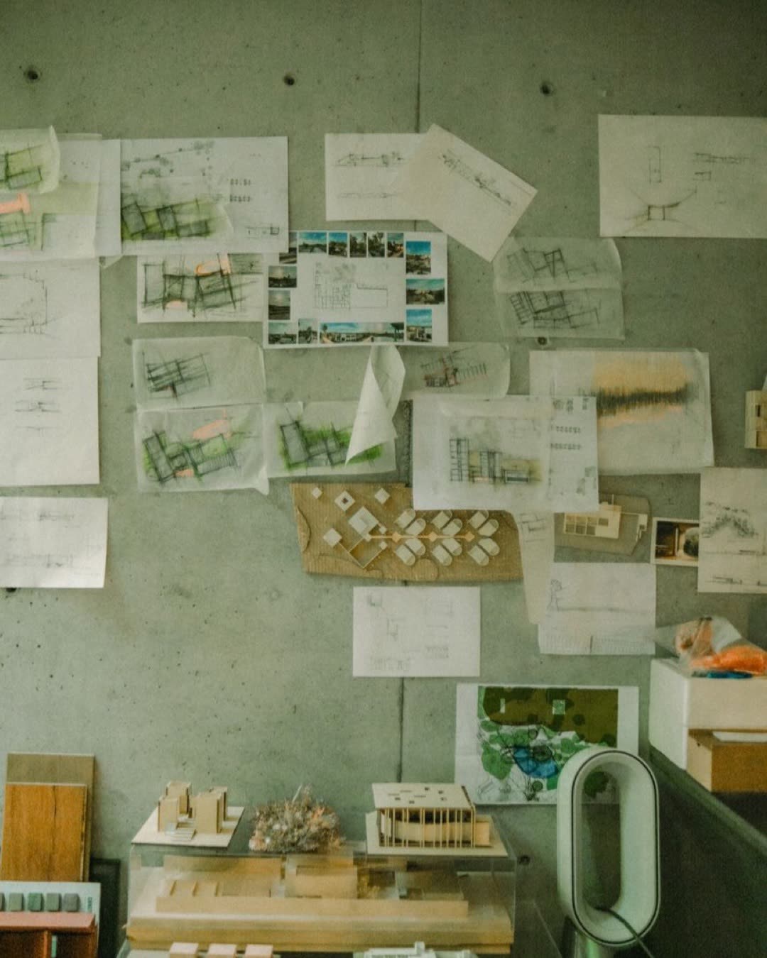 A creative architectural workspace showcasing blueprints and design models on a concrete wall.