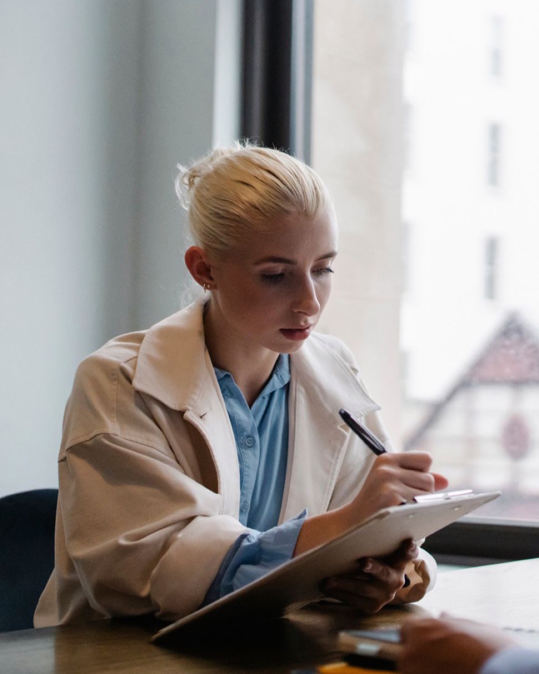 Woman writing notes during a beauty consultation indoors.