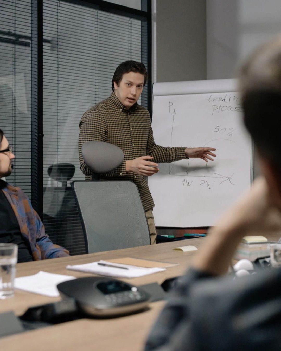 Businessman giving a presentation to colleagues in modern office setting, emphasizing teamwork and communication.