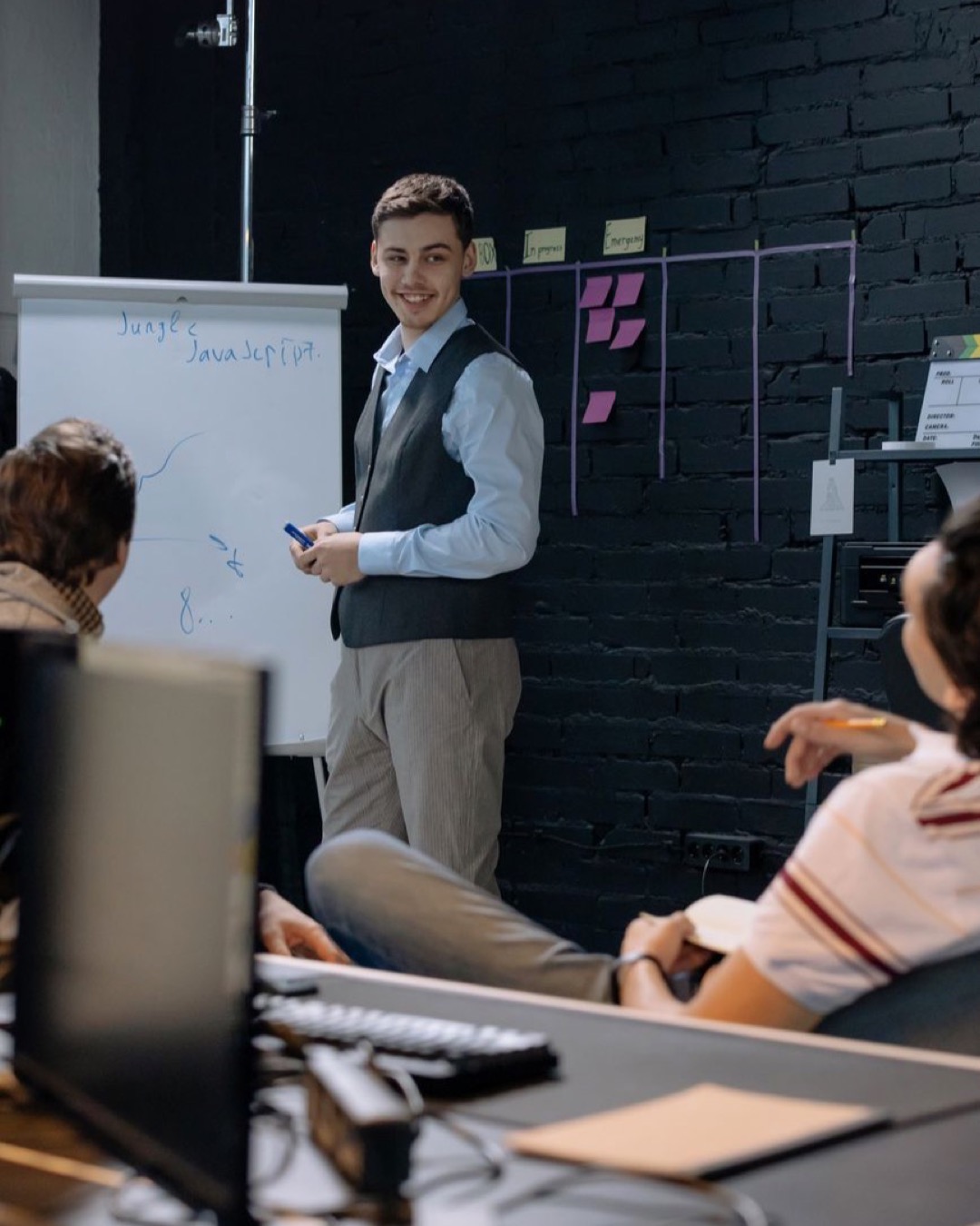 Young professionals discussing work in an office space while using a whiteboard for presentations and planning.