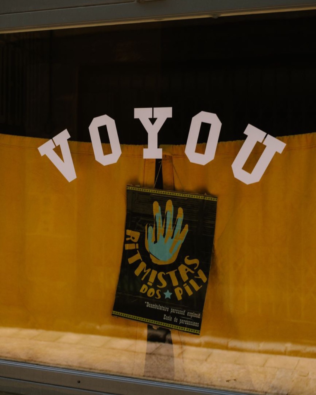 Decorative window display with a poster and yellow curtains, featuring bold text.