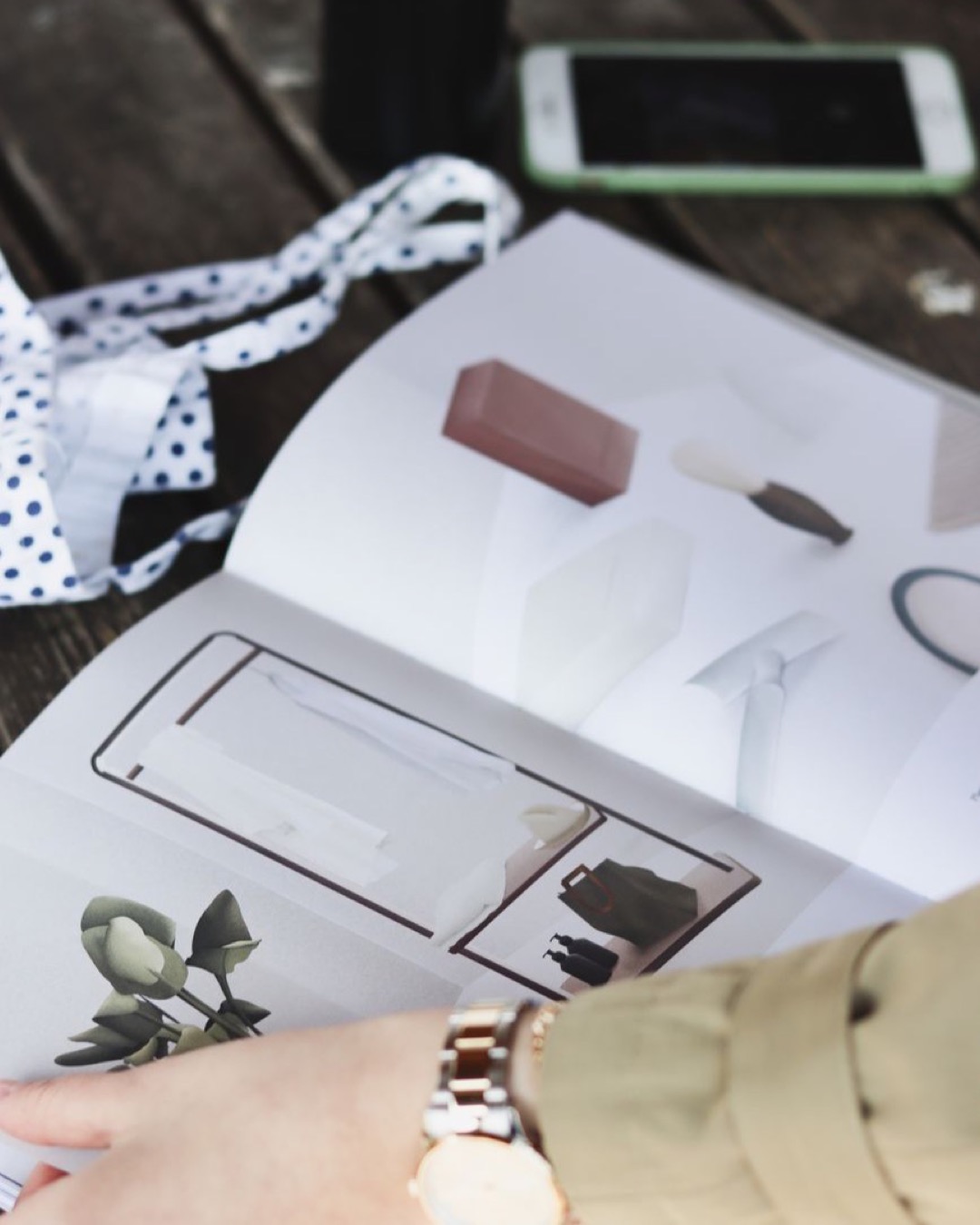 Close-up of a person flipping through a fashion magazine outdoors, showcasing elegant designs.