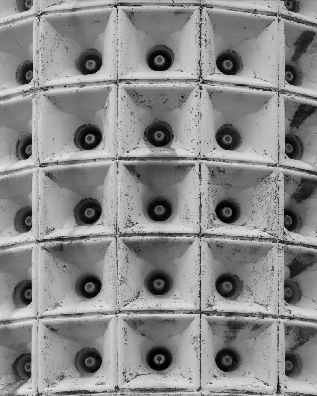 Black and white close-up of a symmetrical speaker array with grille.