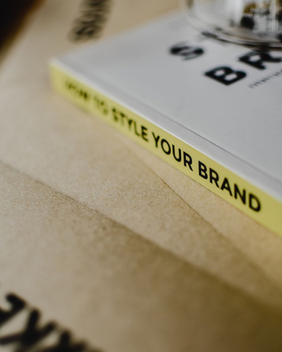 A close-up of a book titled "How to Style Your Brand" on a paper background.