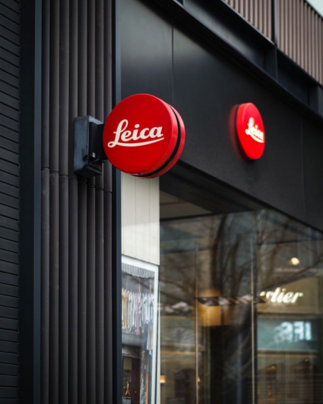 Vertical shot of a modern Leica store facade, highlighting urban architectural design.