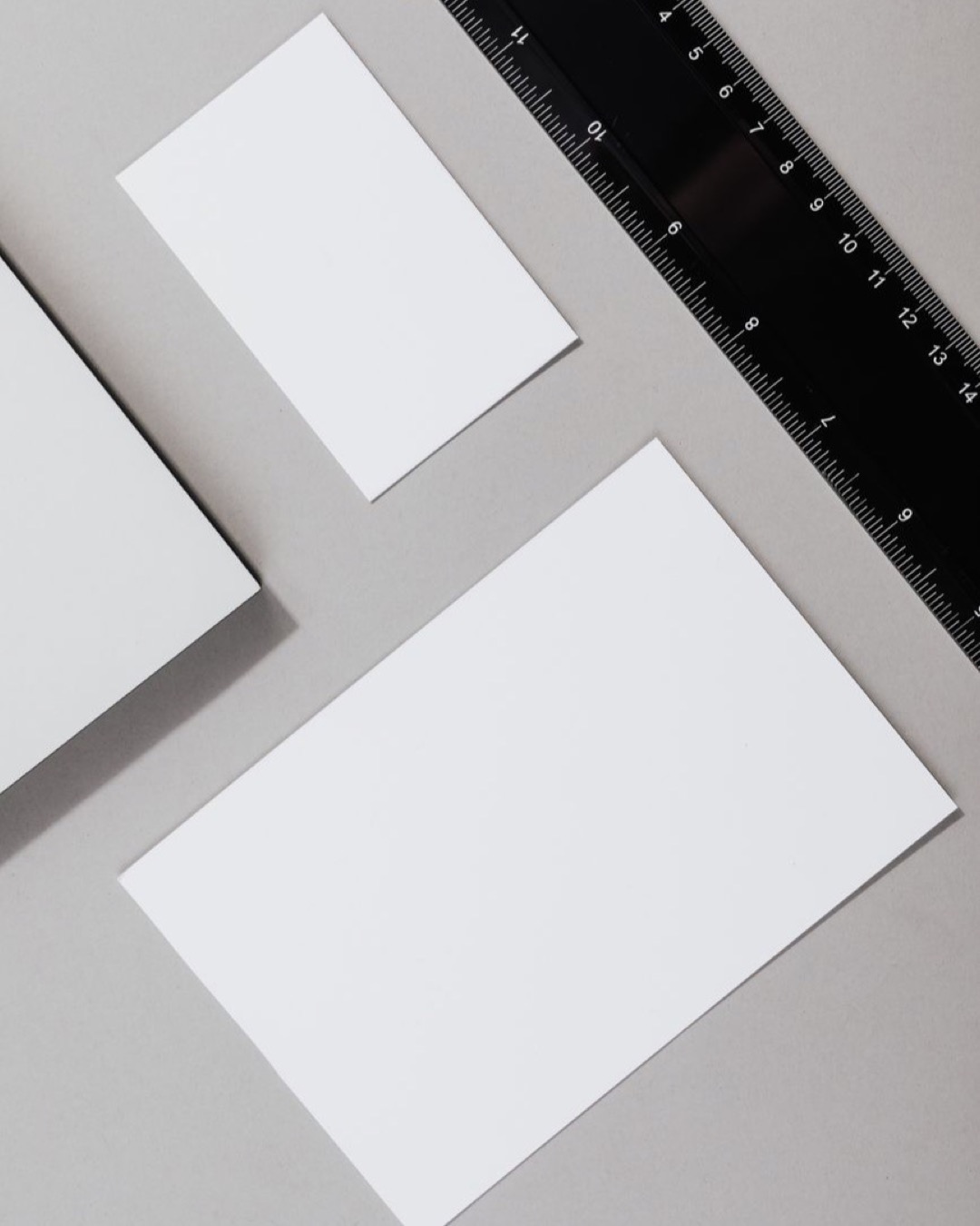 Flat lay of blank paper sheets and ruler on a gray background, ideal for office themes.