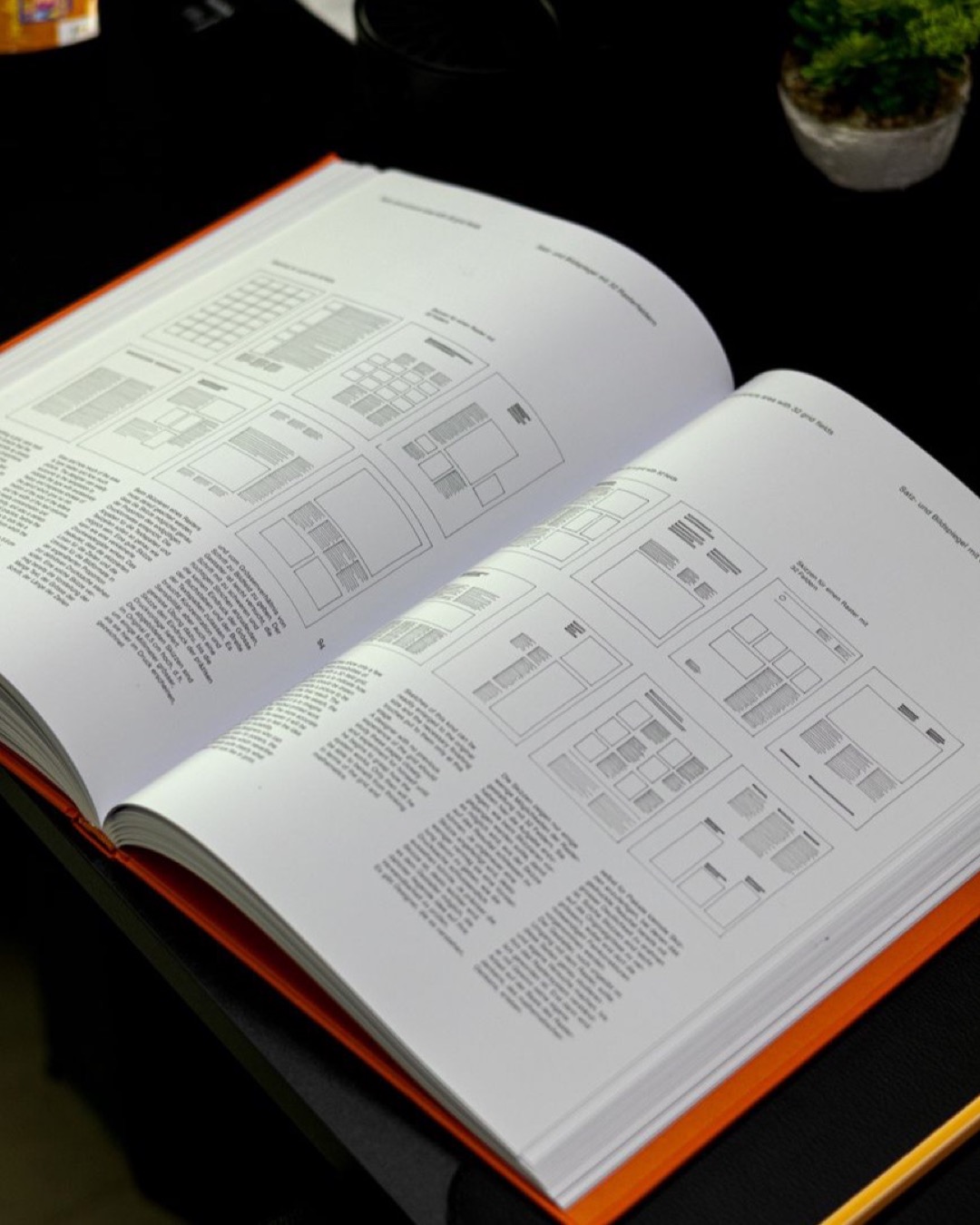 Open book with design layouts and grid systems on a workspace table showcasing editorial design.