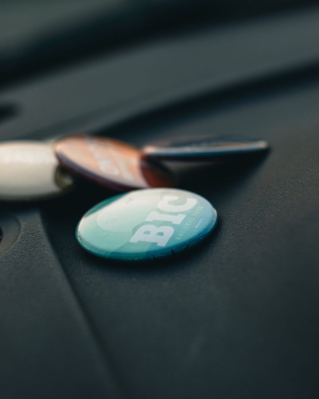 A close-up view of various colorful button pins laid on a dark textured surface.
