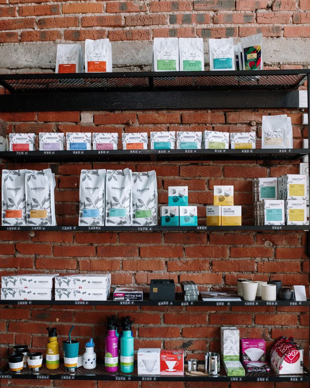 Brick wall shelving in a café with various coffee products and modern decor.