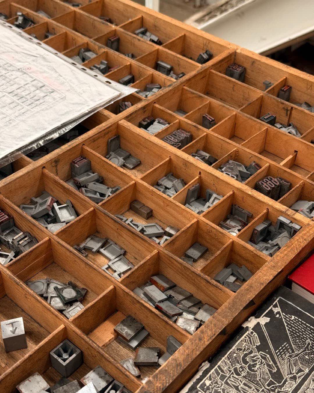 Close-up of vintage letterpress printing blocks in a wooden tray, depicting historic printing techniques.