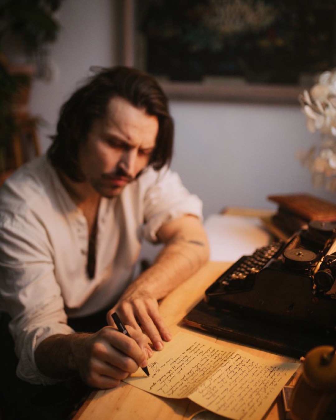 A man pens a letter using a typewriter, evoking a vintage writing atmosphere.