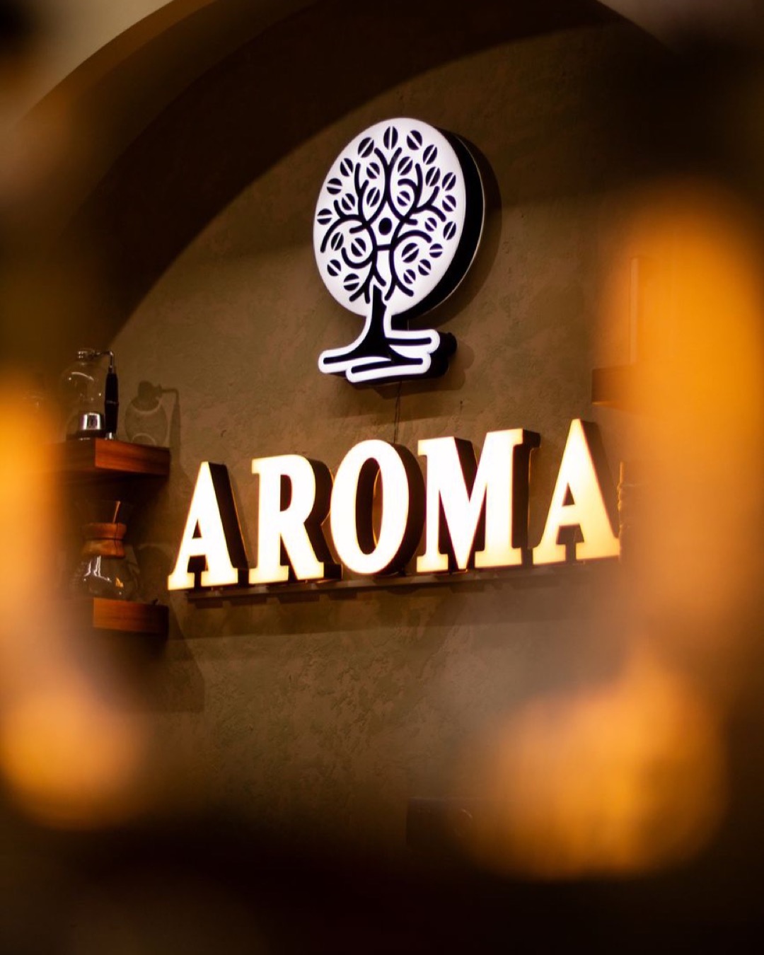 A warm and inviting illuminated Aroma sign in a cozy cafe setting.