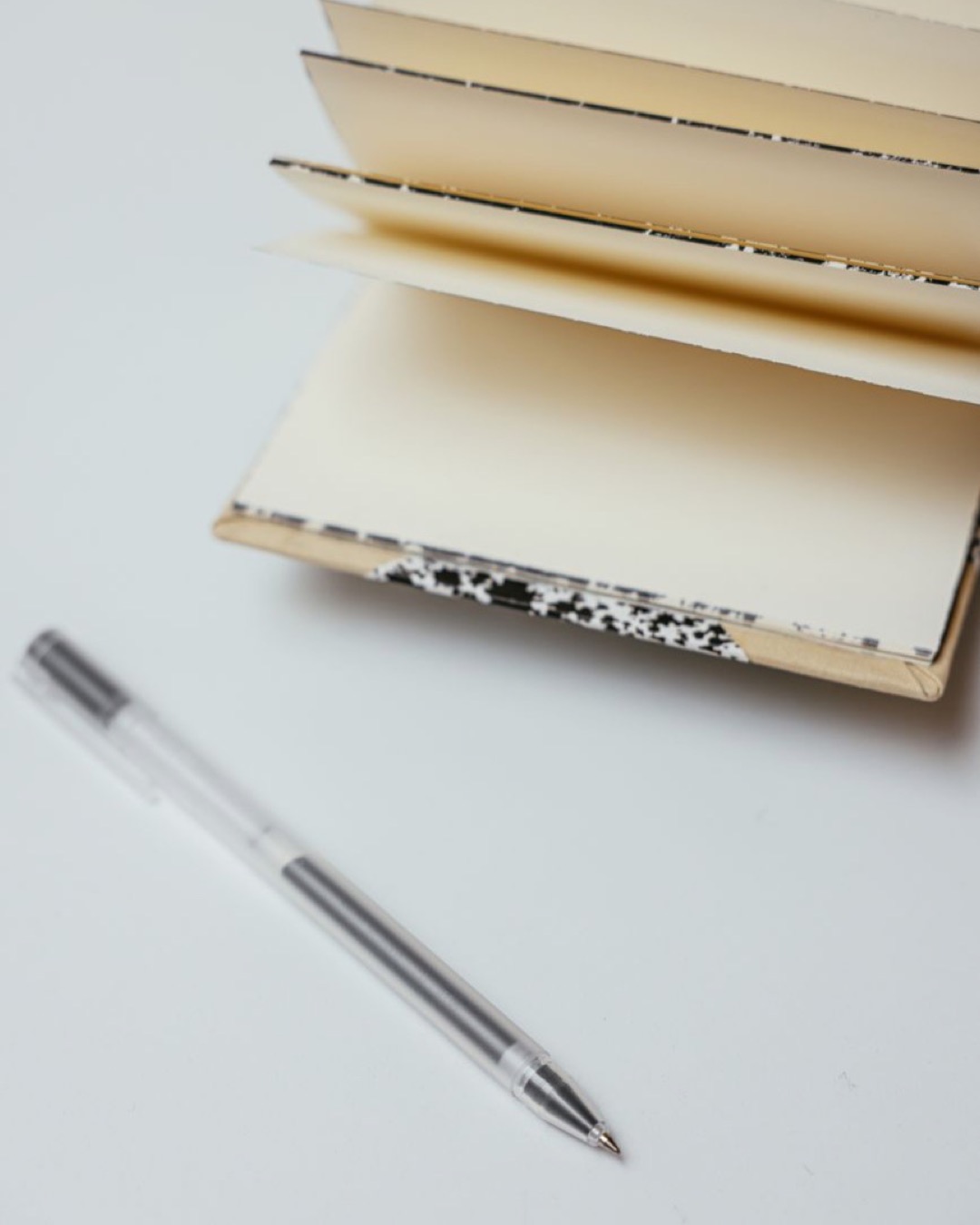 Minimalist setup of an open notebook and pen on a white surface, perfect for writers.