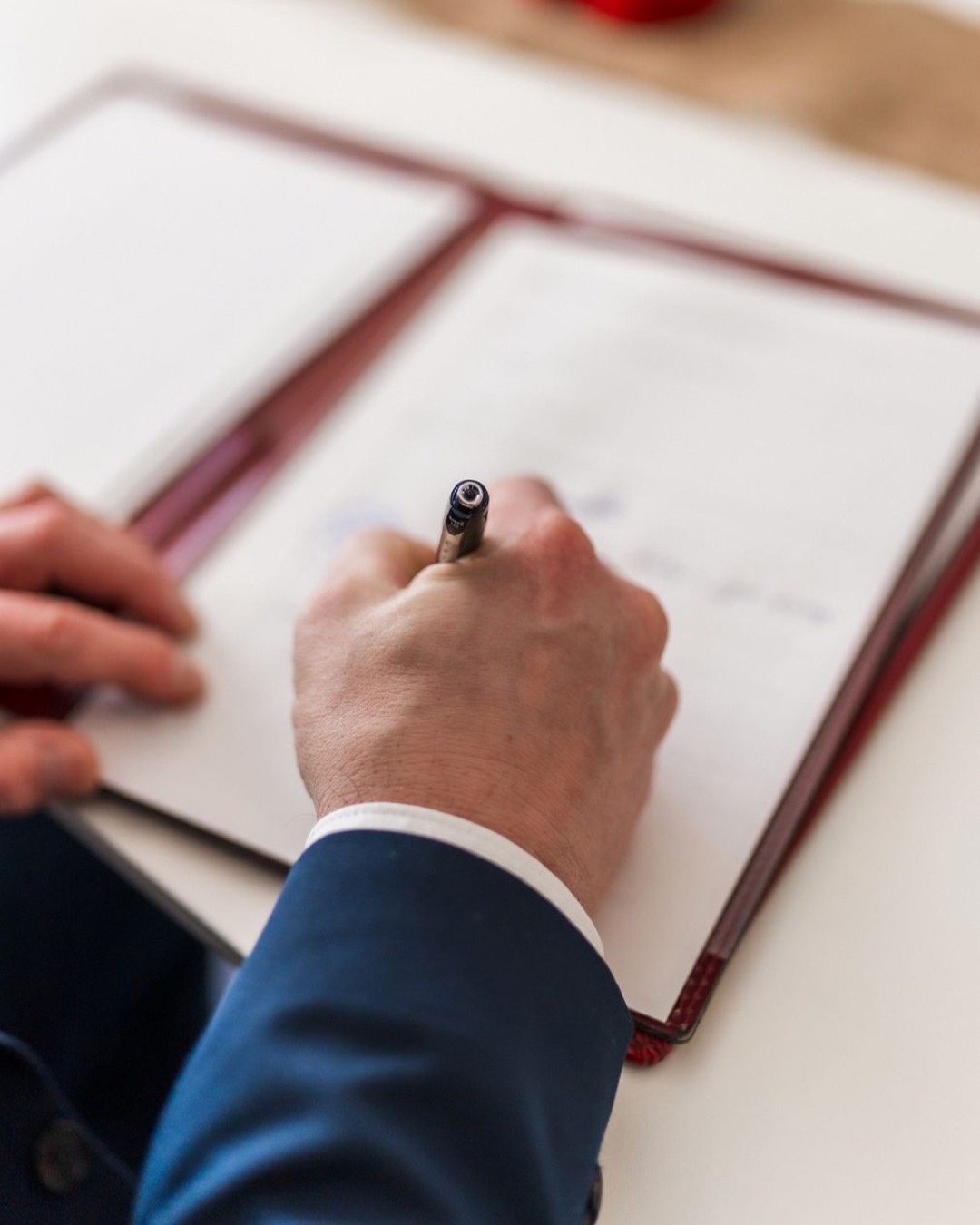 Close-up of a businessman signing a document in a formal office environment.