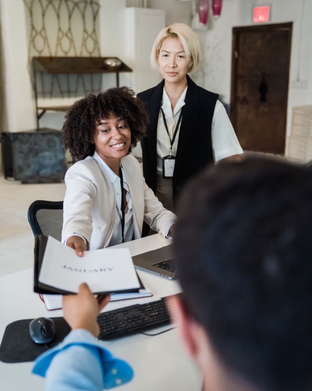 Three diverse colleagues collaborate in a modern office environment, exchanging a document.