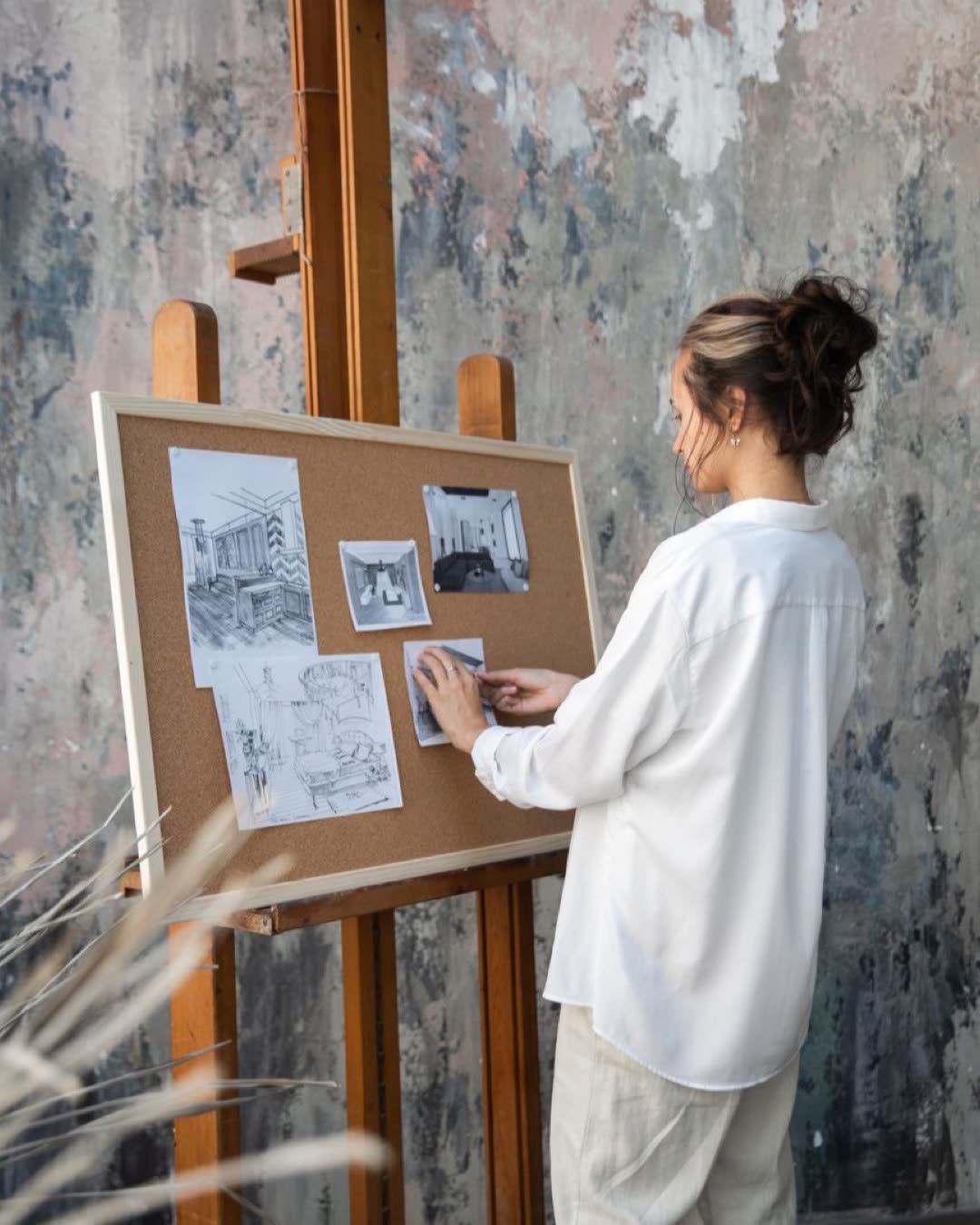 Woman showcases architectural sketches on an easel in her studio.