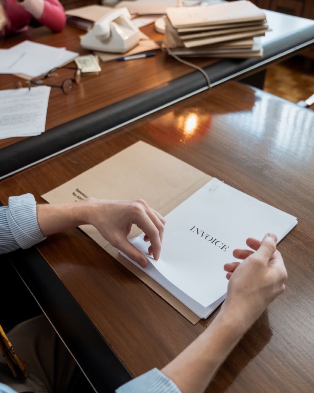 Hands sorting invoices on an office desk, showcasing administrative work indoors.