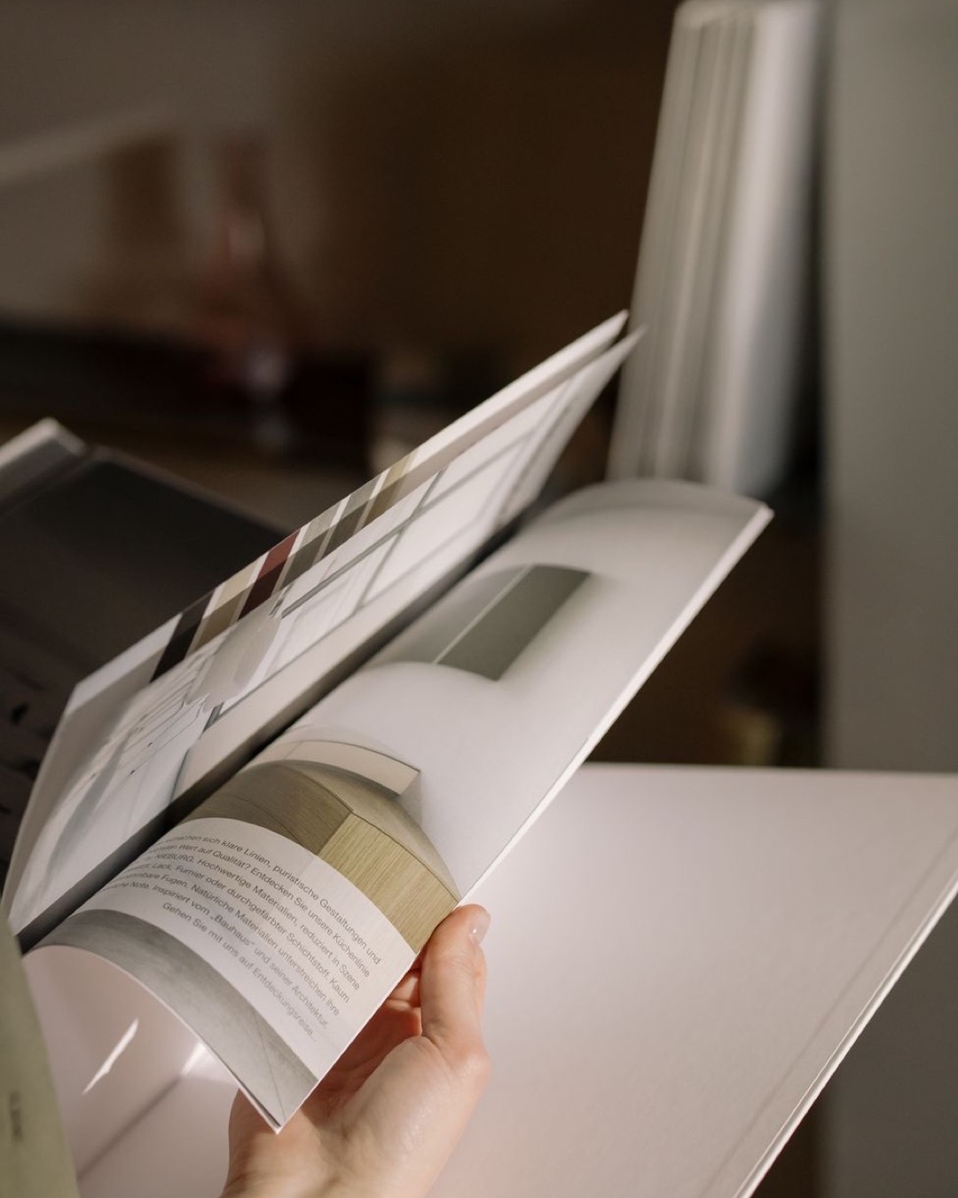Close-up of a hand flipping through a magazine indoors, highlighting modern interior design content.