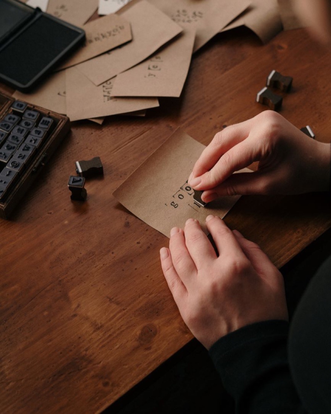 A handmade invitation with elegant script placed on a rustic wooden table with surrounding crafting tools.