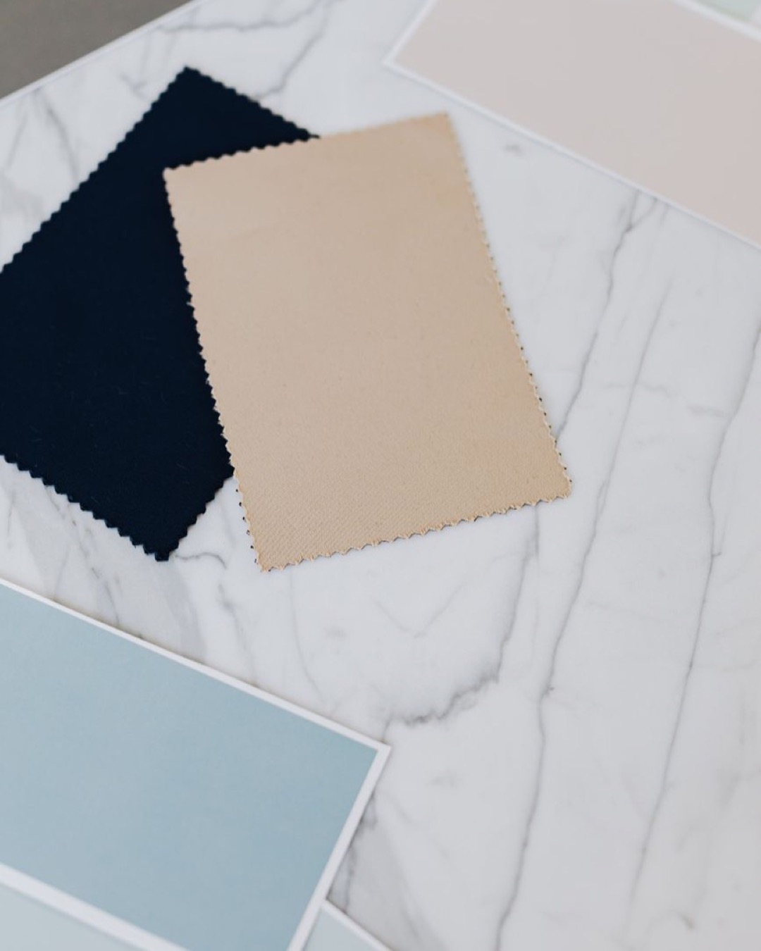 Arranged color swatches and paper samples on a marble table, perfect for design projects.