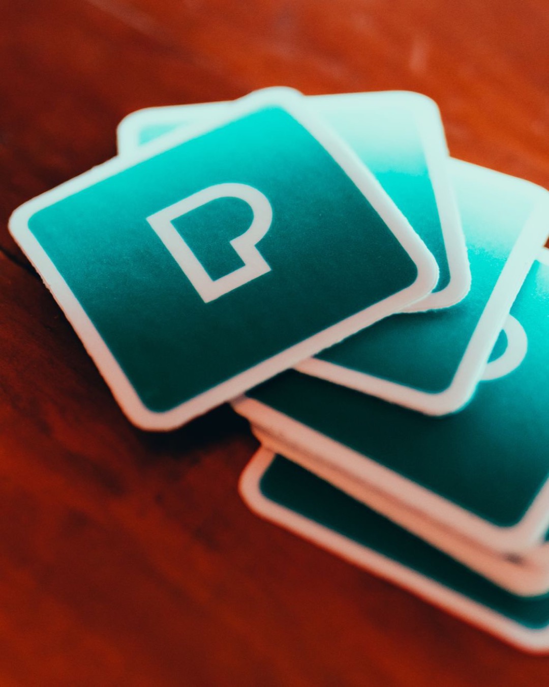 Close-up of a stack of square design cards on a wooden table with a stylish symbol.
