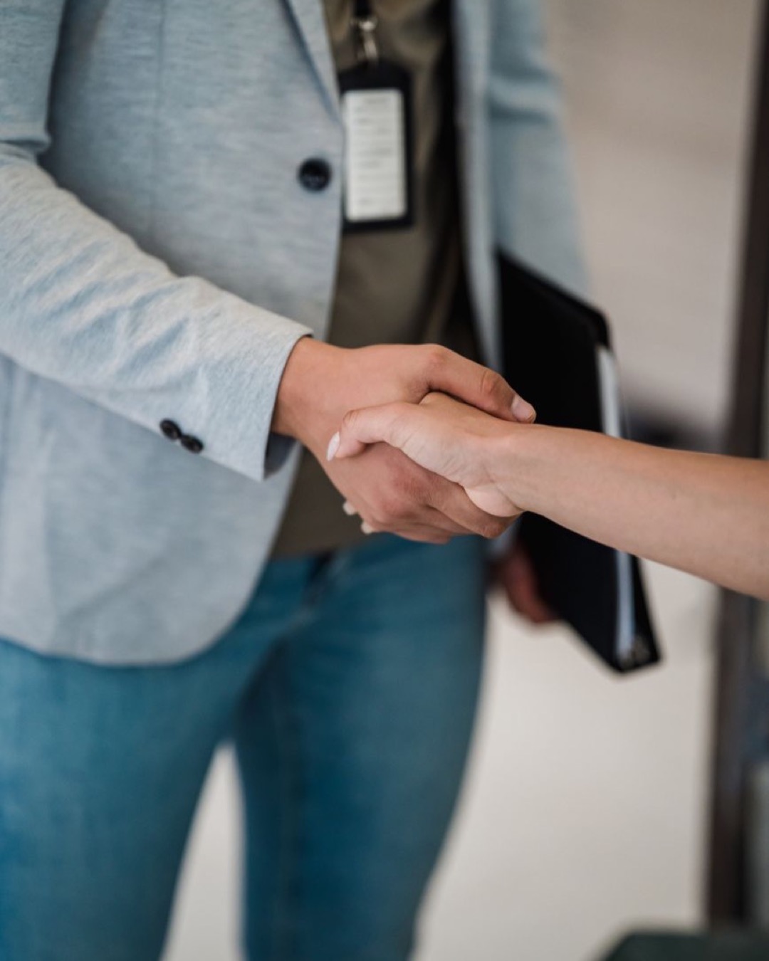 Close-up of two professionals shaking hands in a business meeting setting.