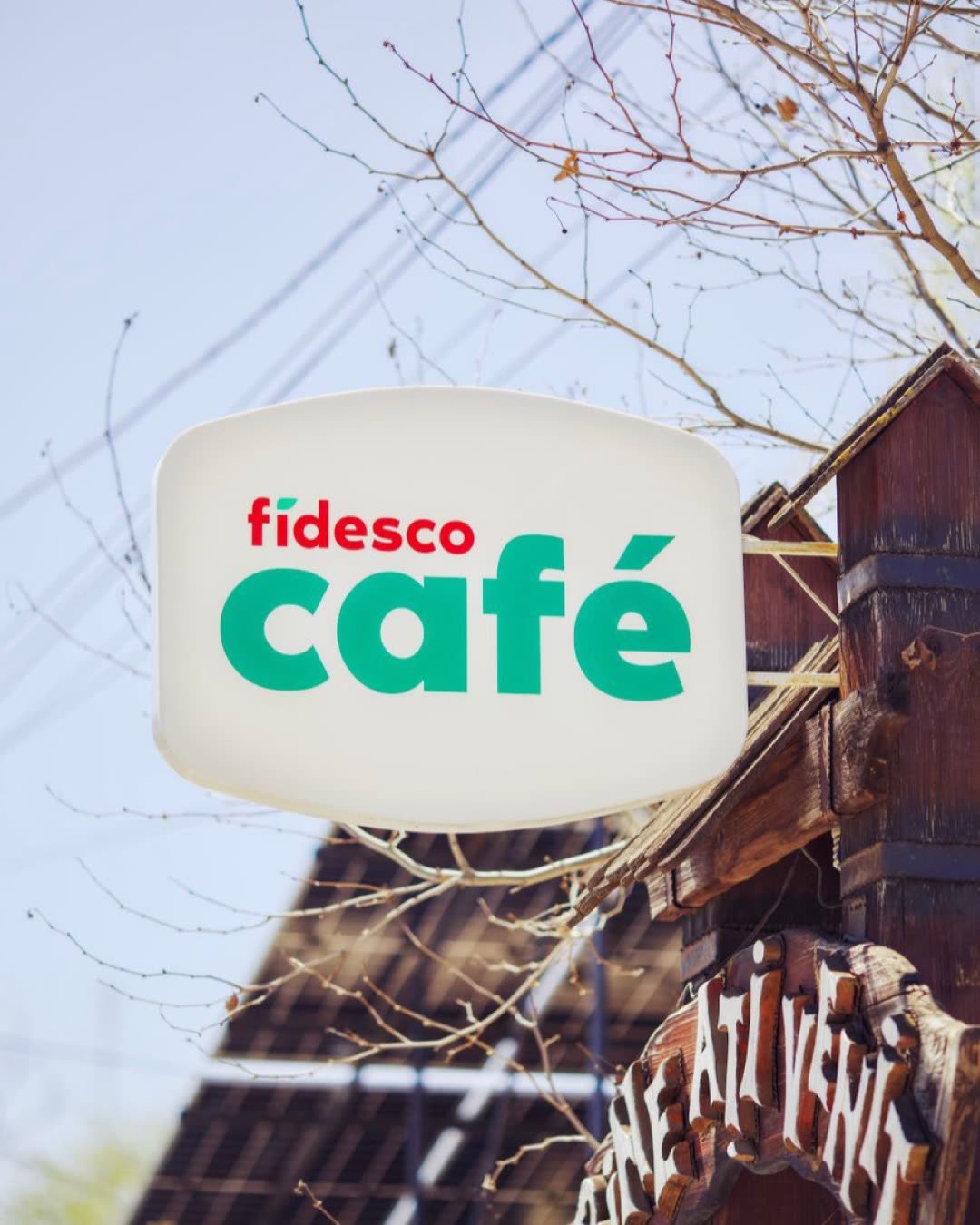 Outdoor sign of Fidesco Café with rustic wooden detail and leafless branches.