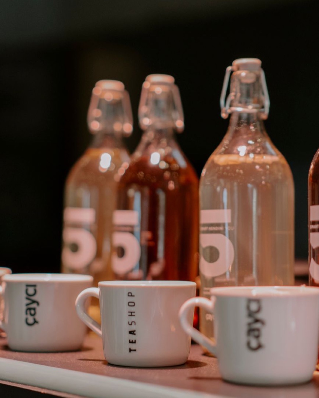 Stylish assortment of glass bottles and cups on a cafe table inside a tea shop.