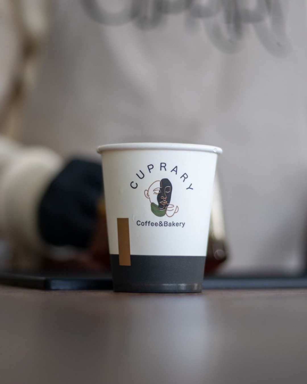 A stylish coffee cup from a Saudi Arabian bakery, featuring a modern logo design.