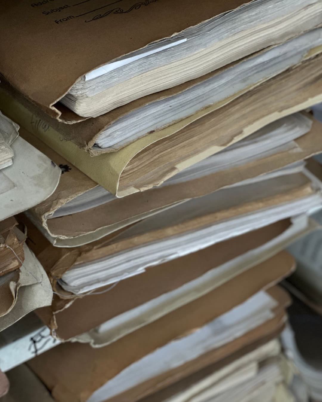 Close-up of old paper files stacked in vintage brown folders, organized and archived.