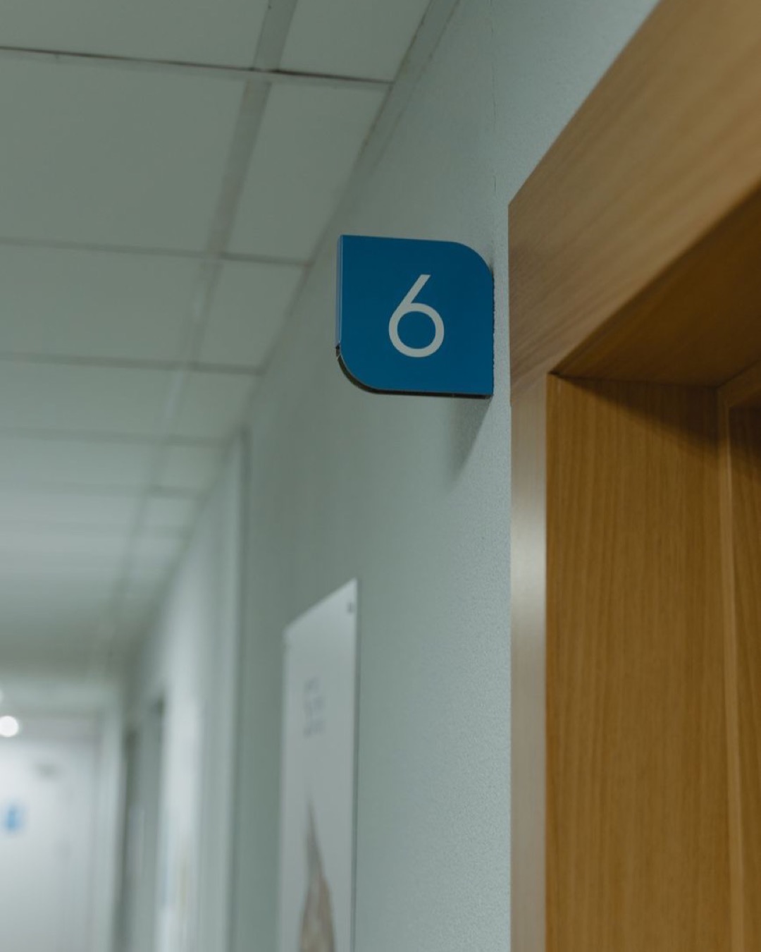 Hallway in a medical facility showcasing room number six sign.