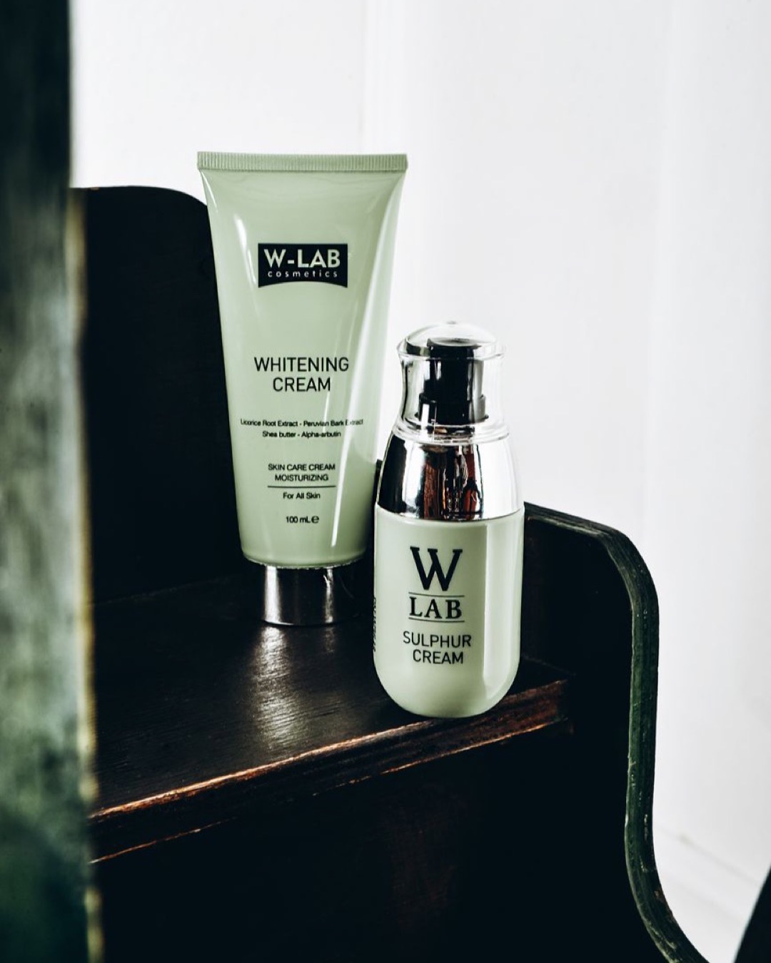 Stylish presentation of W-LAB whitening and sulphur creams on a wooden surface.