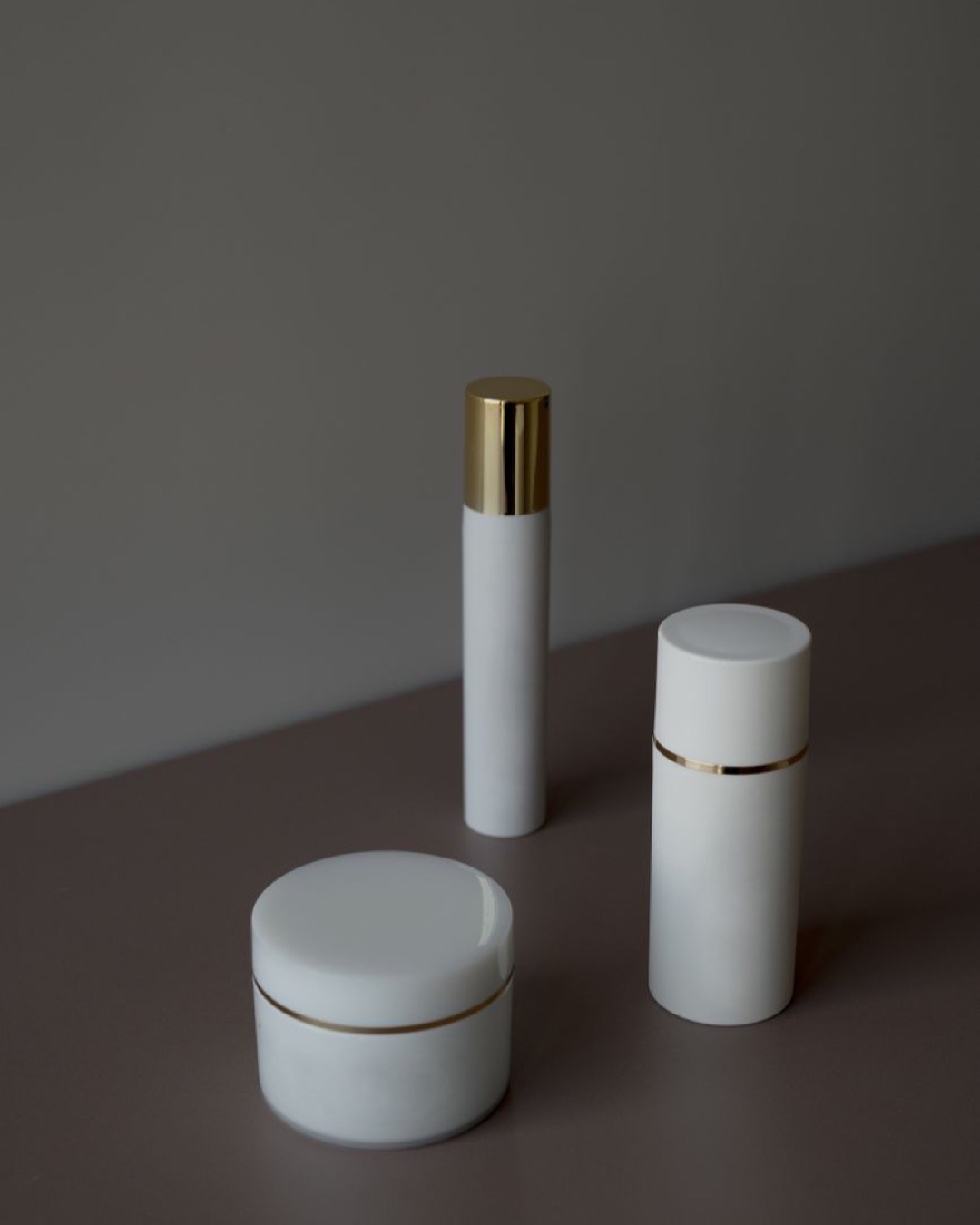 Elegant minimalist shot of skincare product containers with a gray background.