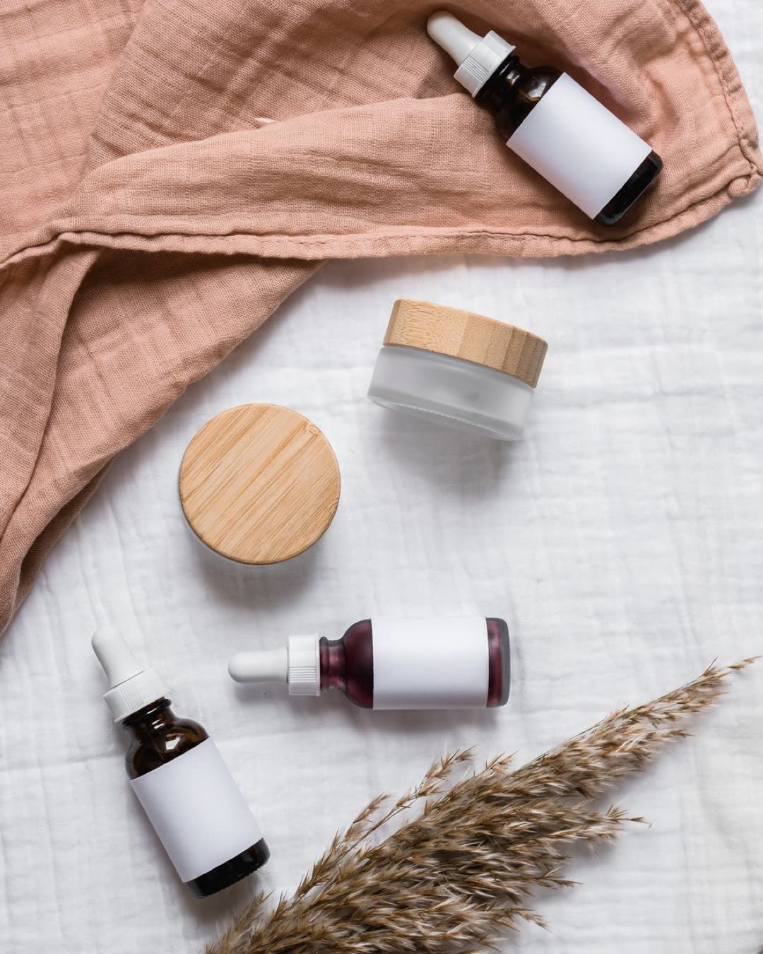 Stylish flat lay of serum bottles and jars on soft fabric with a natural, earthy aesthetic.