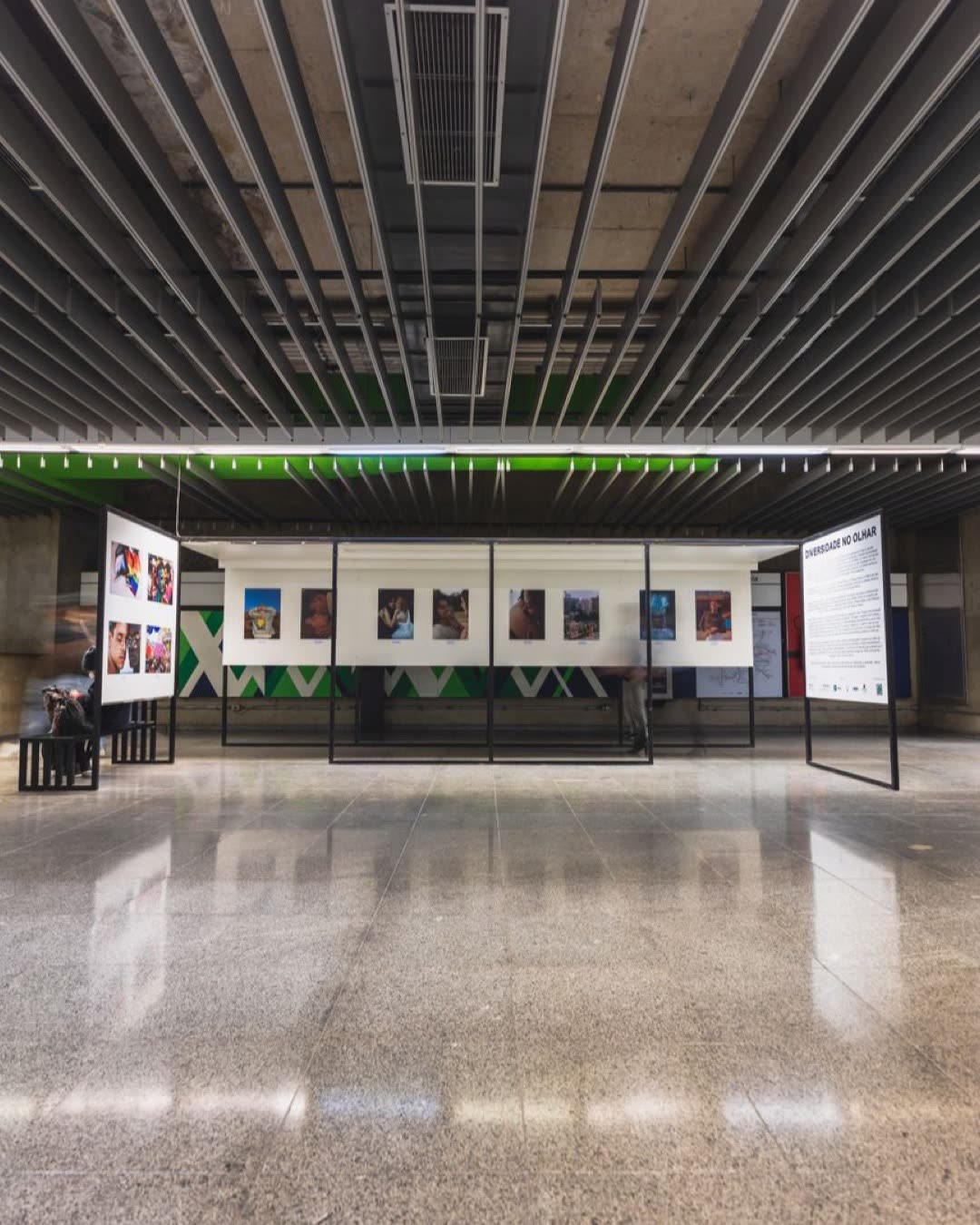Wide-angle view of a modern art exhibition in a spacious gallery with polished tiled floors and ceiling vents.