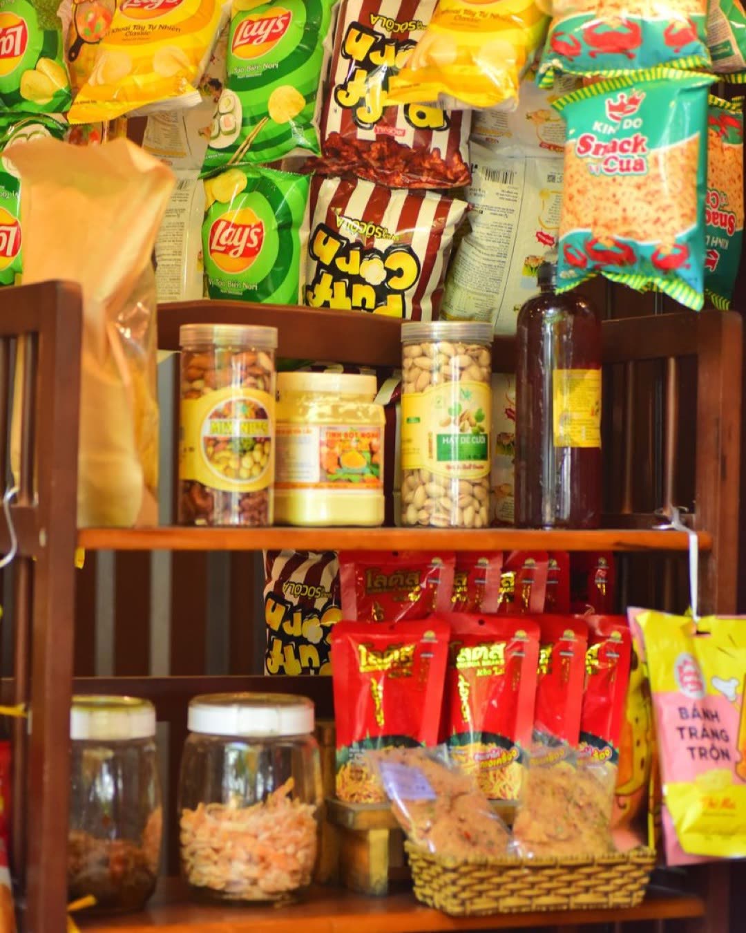 Colorful display of snack bags and bottles on a wooden shop shelf.