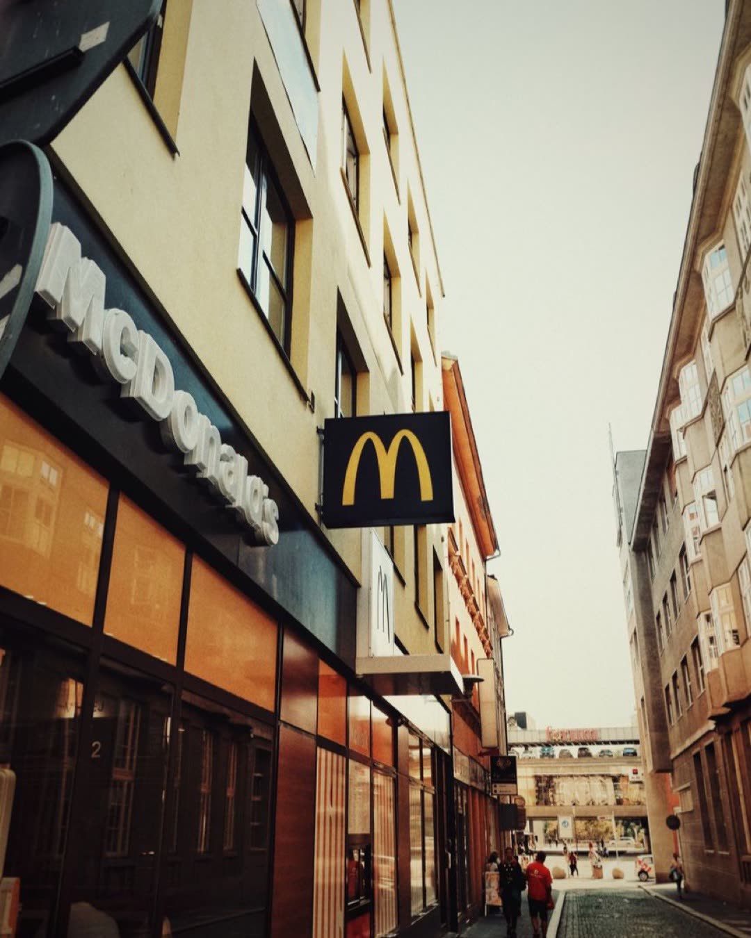 A McDonald's sign on a city street, showing urban architecture during the day.
