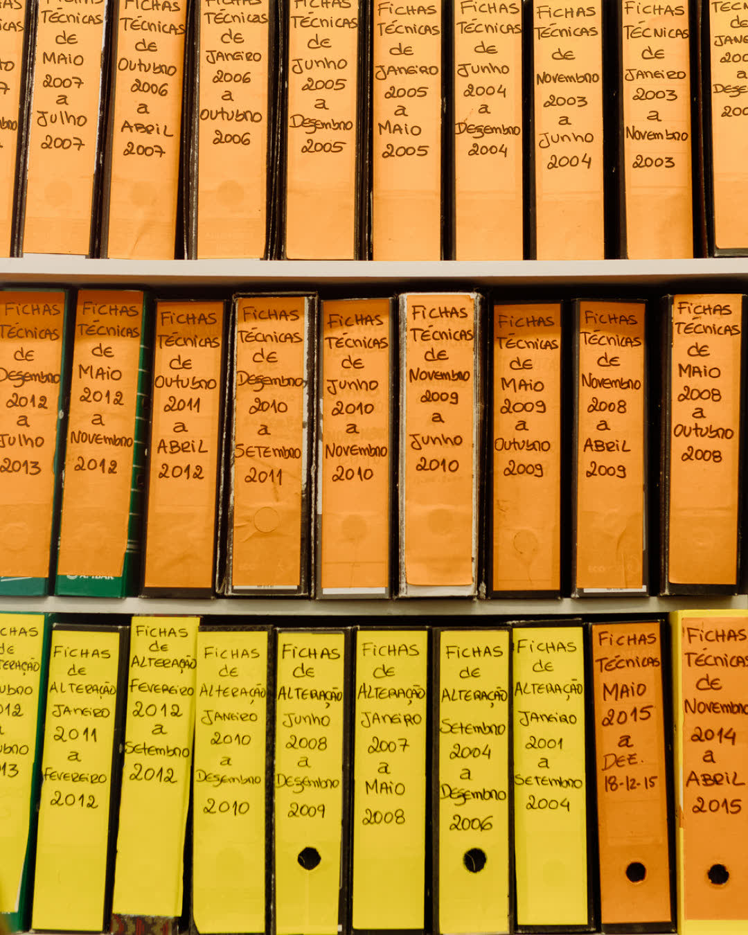 Rows of labeled binder folders on a shelf showcasing organized office files and technical documents.