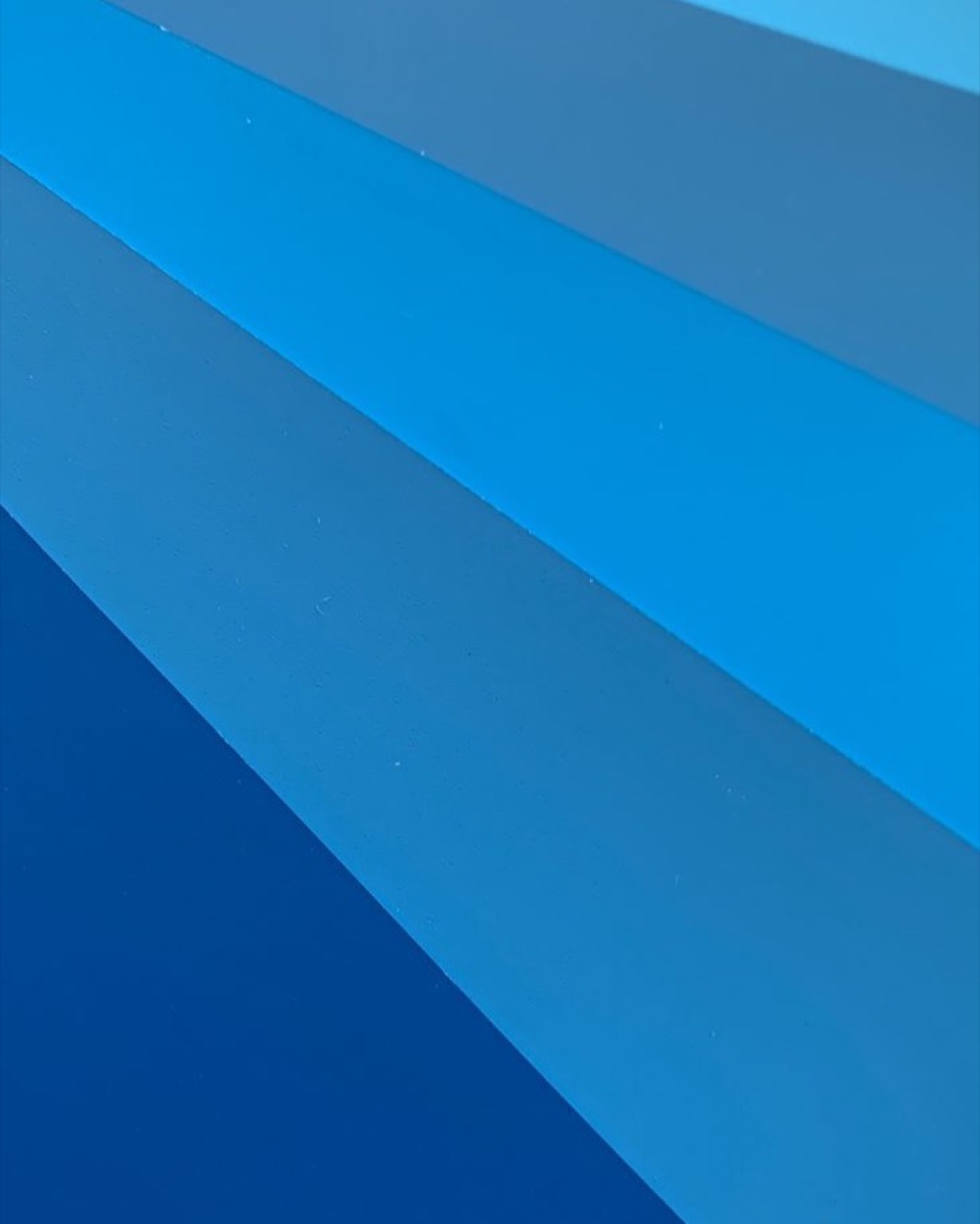 Vibrant blue gradient pattern featuring diagonal stripes, creating an abstract visual texture.
