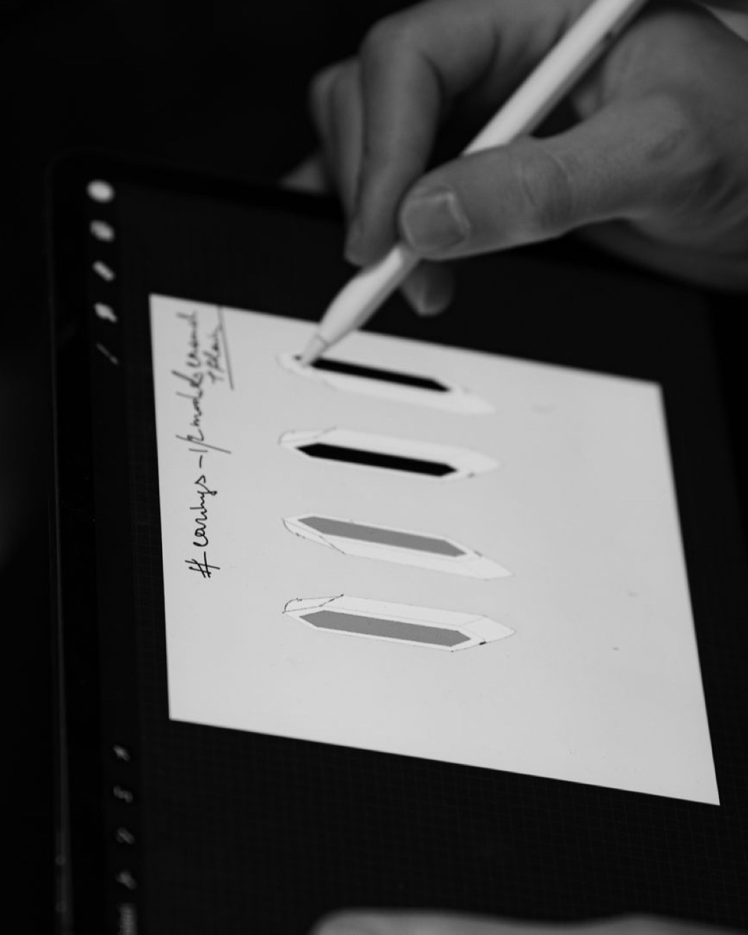 A person using a stylus to design geometric shapes on a tablet in black and white.