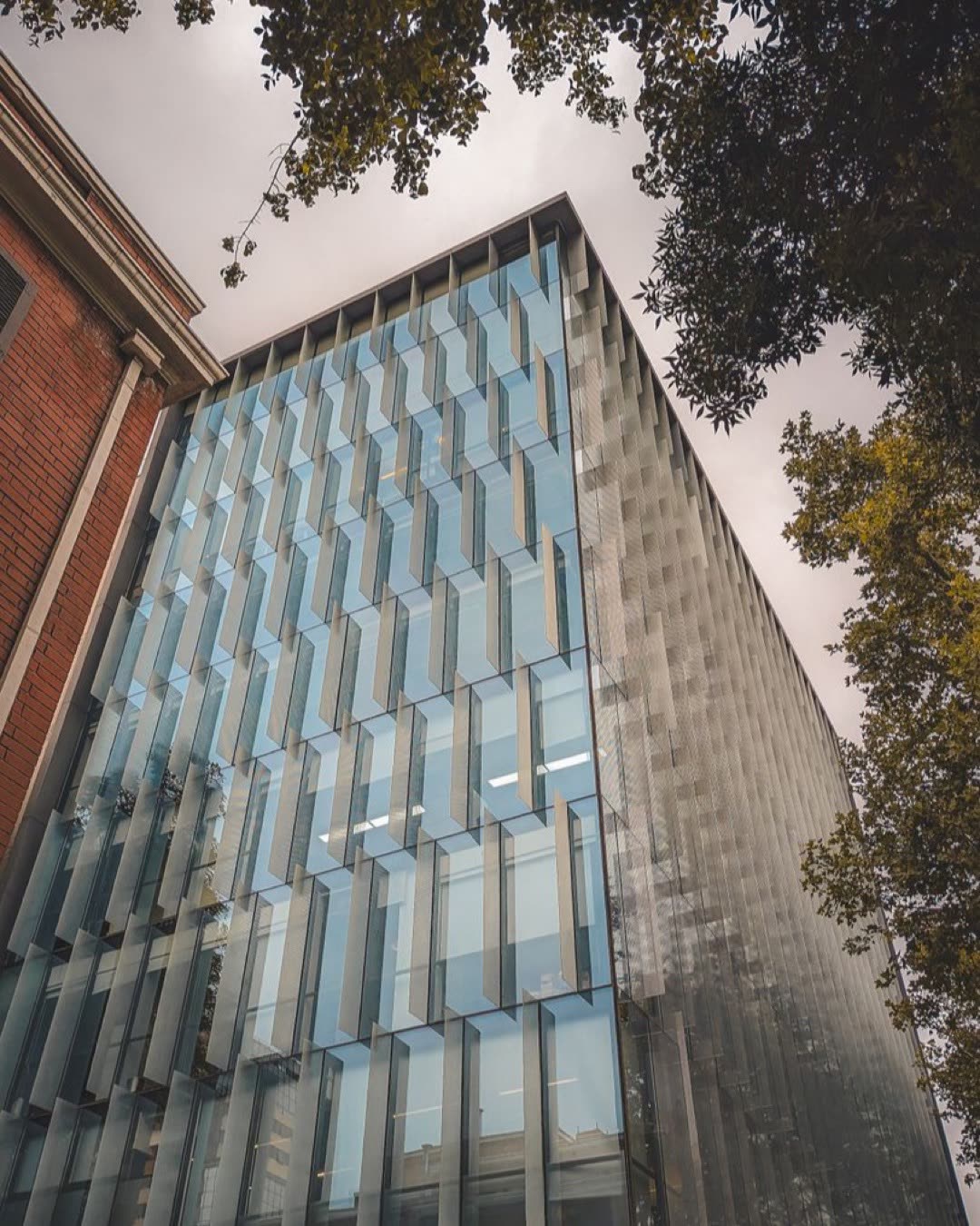 Low angle shot of a modern office building with glass windows and urban architecture.