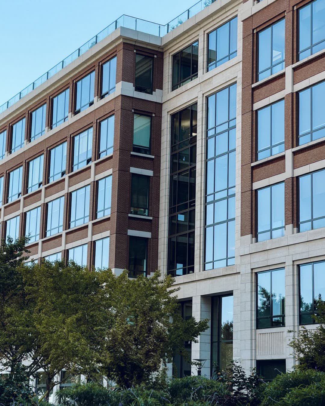 Contemporary office building exterior featuring large glass windows and green surroundings.