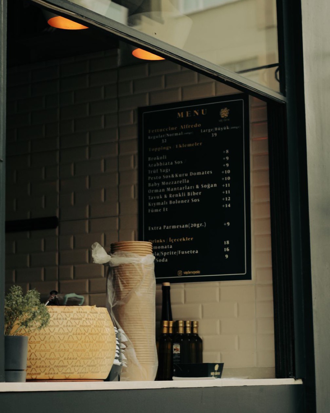 A warm cafe window features a displayed menu alongside inviting decor items, creating a cozy atmosphere.