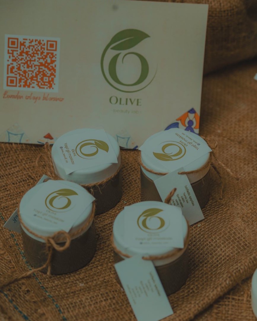 Elegant display of natural beauty products with olive branding on burlap, perfect for eco-conscious consumers.