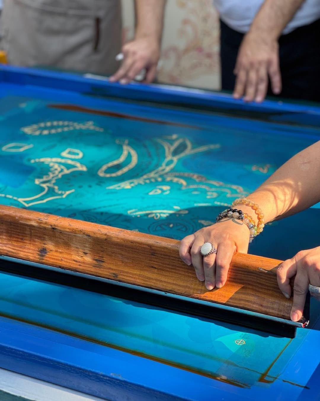 Close-up of artists engaged in traditional screen printing technique, creating unique designs.