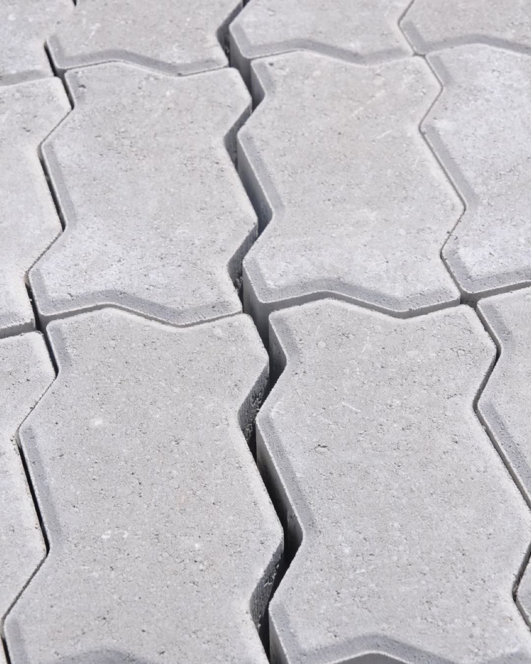 Close-up view of interlocking concrete pavers with a geometric pattern, perfect for outdoor pavements.