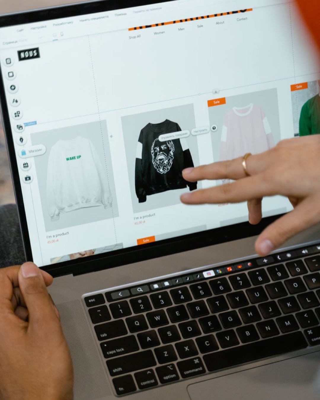 Close-up of hands interacting with a shopping website on a laptop screen indoors.