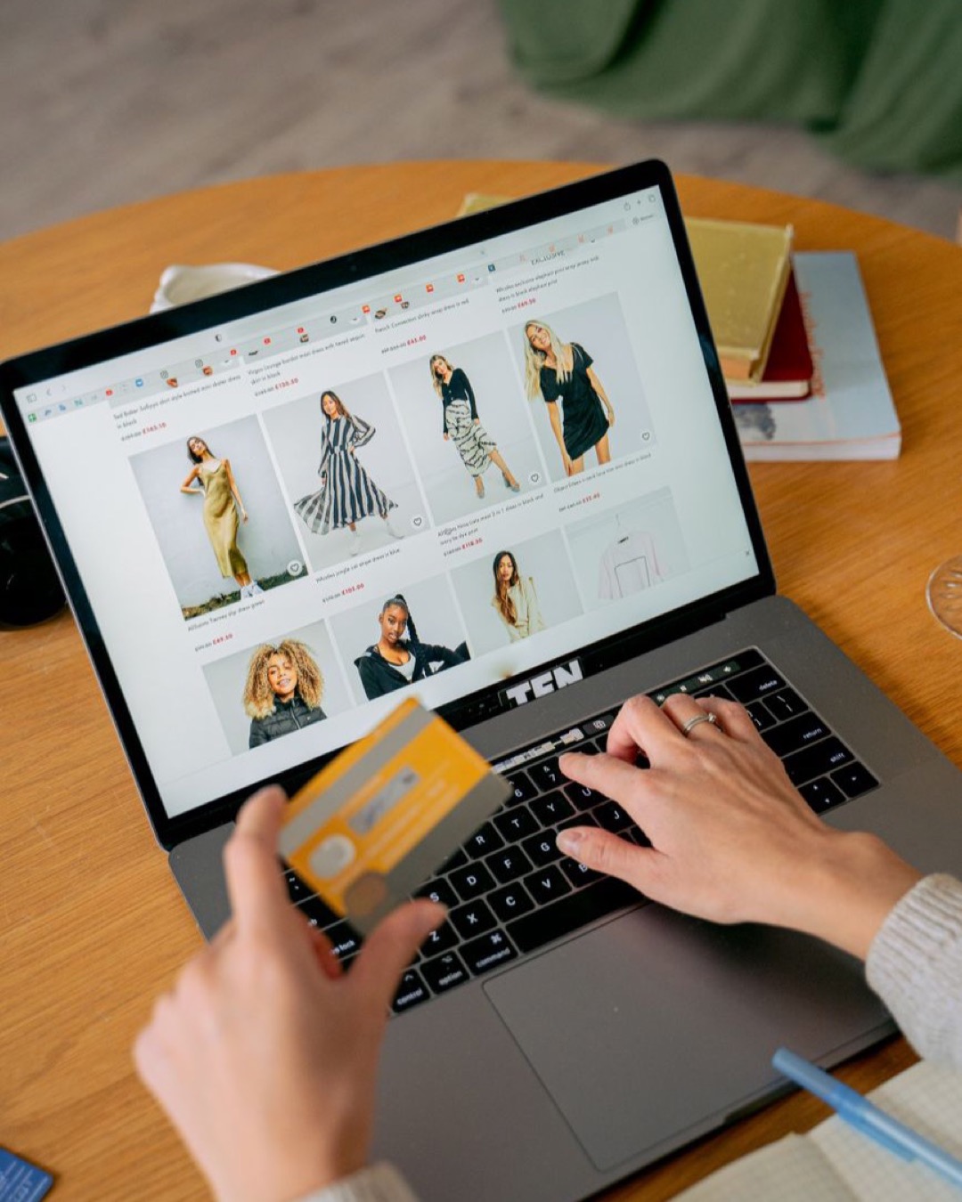 A woman makes an online purchase using a credit card on her laptop, browsing an online fashion store.