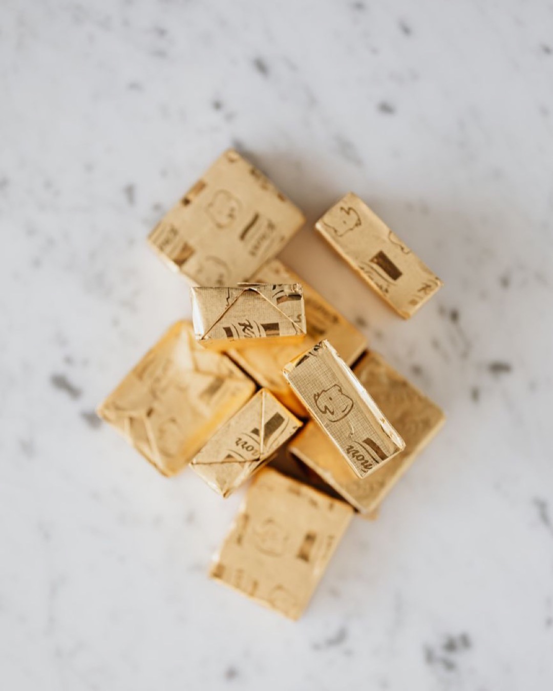 Top view of pile of chicken cubes in golden packages on marble table